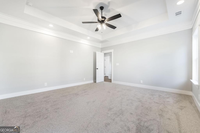 empty room featuring crown molding, ceiling fan, a tray ceiling, and carpet floors