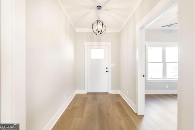 foyer entrance featuring hardwood / wood-style flooring, crown molding, and an inviting chandelier