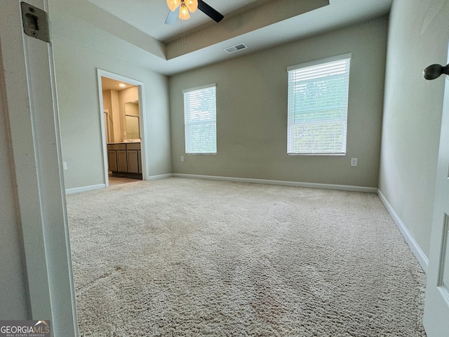 carpeted empty room featuring ceiling fan and a raised ceiling