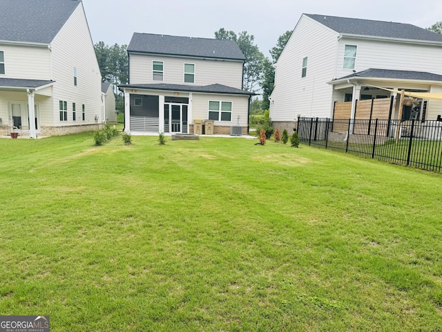 rear view of property featuring cooling unit, a lawn, and a sunroom