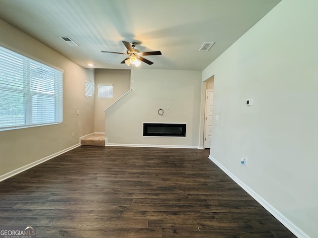 unfurnished living room featuring ceiling fan and dark hardwood / wood-style flooring