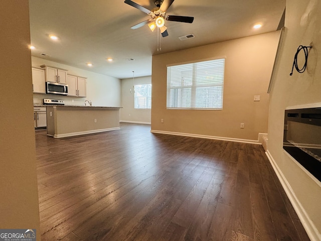 unfurnished living room with sink, dark hardwood / wood-style floors, and ceiling fan