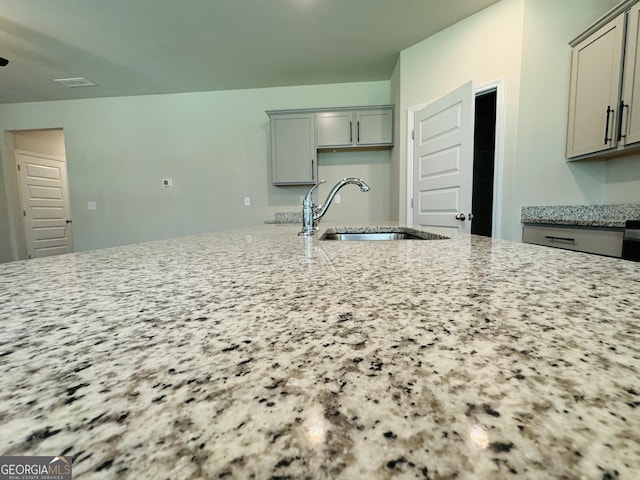 kitchen with sink, gray cabinetry, and light stone counters