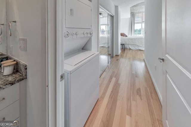 clothes washing area featuring stacked washer / drying machine and light hardwood / wood-style floors