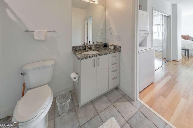 bathroom with vanity, toilet, stacked washer / drying machine, and wood-type flooring