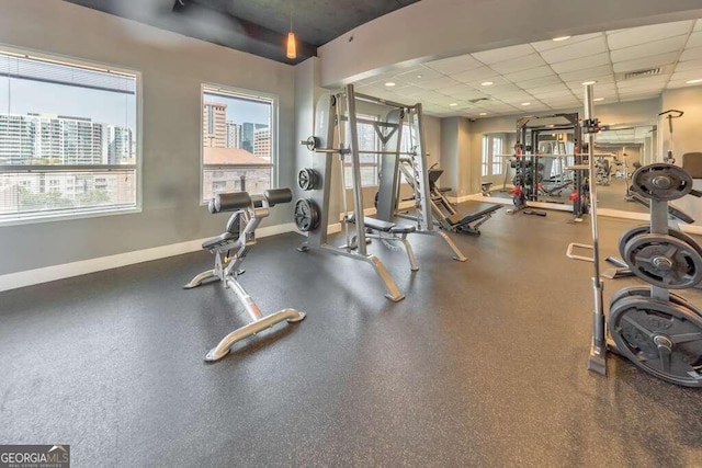 exercise room with a healthy amount of sunlight and a drop ceiling