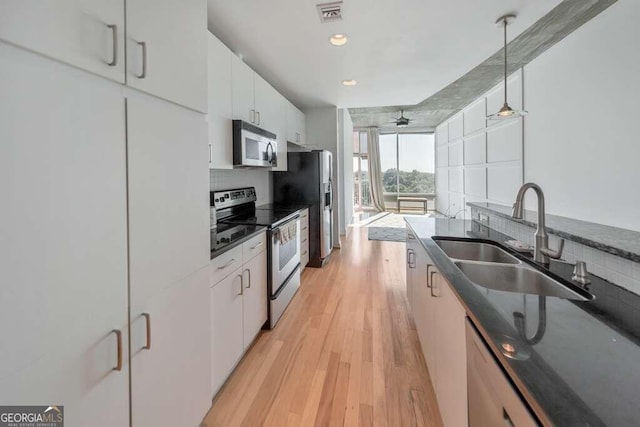 kitchen featuring pendant lighting, white cabinetry, light hardwood / wood-style flooring, sink, and appliances with stainless steel finishes