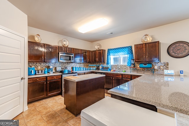 kitchen with sink, kitchen peninsula, dark brown cabinets, stainless steel appliances, and decorative backsplash