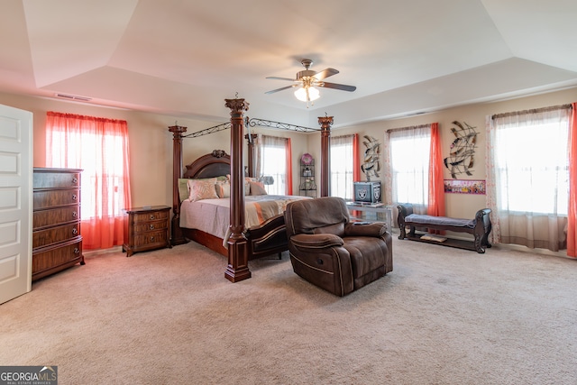 carpeted bedroom with a tray ceiling and ceiling fan