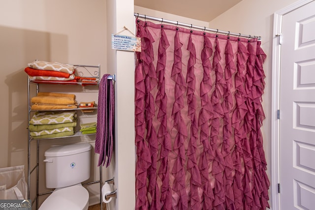 bathroom featuring toilet and curtained shower