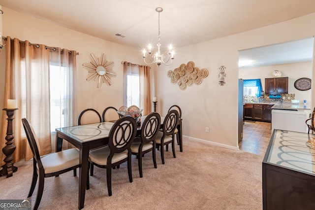 dining area featuring a notable chandelier and light colored carpet