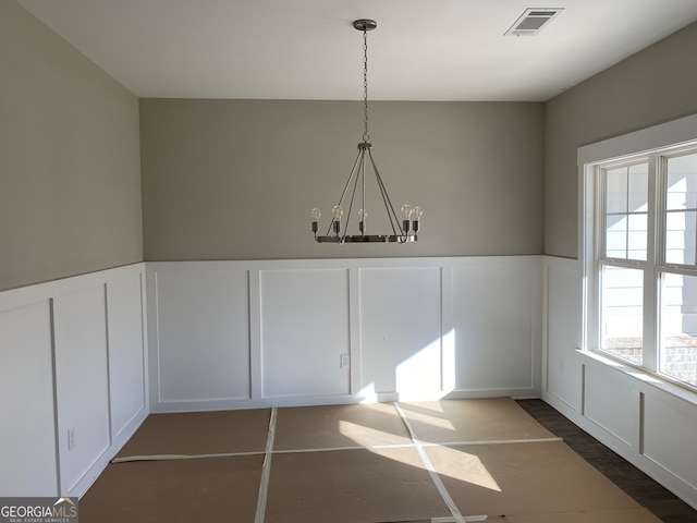 unfurnished dining area with dark tile patterned flooring and a chandelier