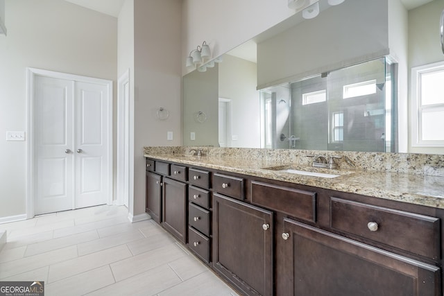 bathroom with plenty of natural light, double vanity, a stall shower, and a sink