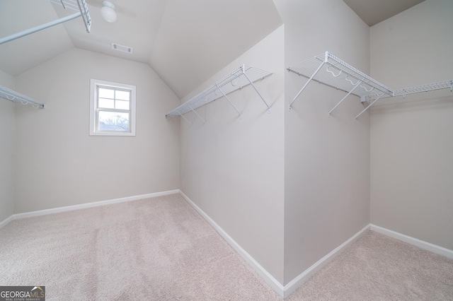 spacious closet with lofted ceiling, visible vents, and carpet