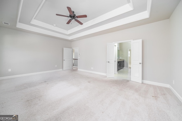 unfurnished bedroom with visible vents, baseboards, light carpet, and a tray ceiling