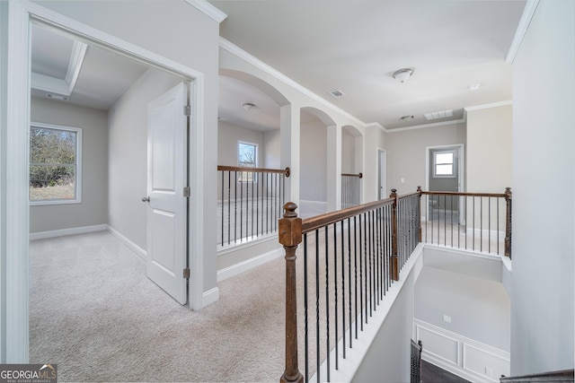 corridor with an upstairs landing, light colored carpet, crown molding, baseboards, and visible vents