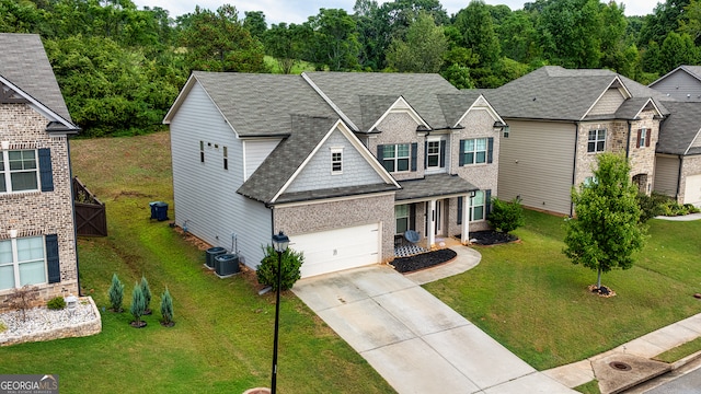 view of front of house featuring cooling unit, a garage, and a front lawn