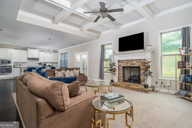 living room featuring wood-type flooring, coffered ceiling, a fireplace, ornamental molding, and ceiling fan