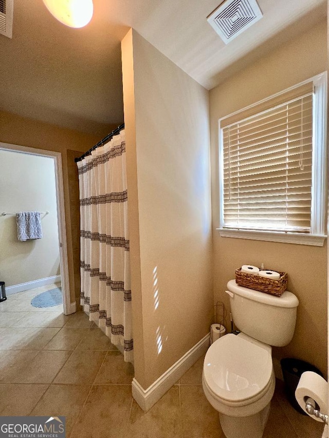 bathroom featuring tile patterned flooring, a shower with shower curtain, and toilet