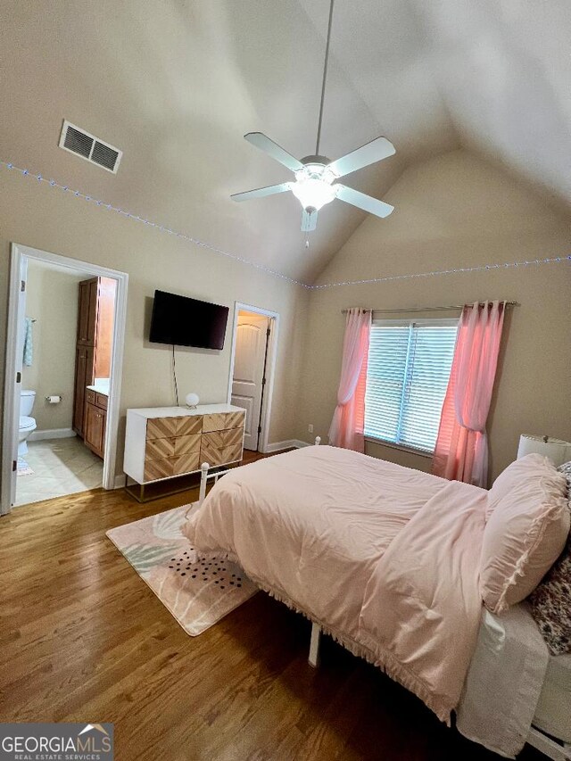 bedroom with light hardwood / wood-style floors, vaulted ceiling, ceiling fan, and ensuite bathroom