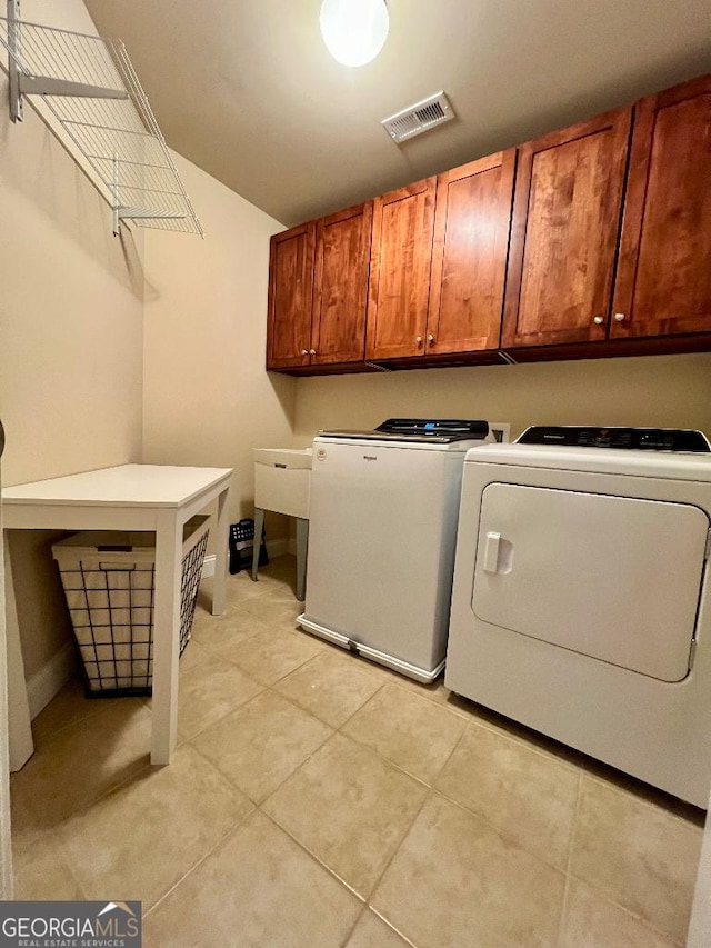 laundry room featuring light tile patterned flooring, cabinets, and washing machine and clothes dryer