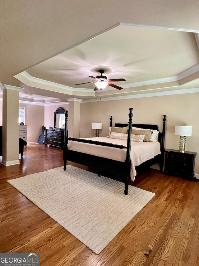 bedroom featuring a tray ceiling, ceiling fan, crown molding, and hardwood / wood-style flooring