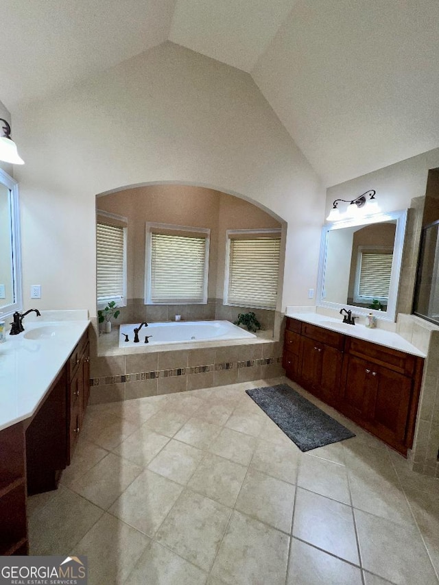 bathroom with tile patterned floors, tiled bath, vanity, and lofted ceiling