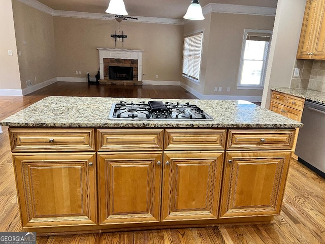 kitchen with tasteful backsplash, a stone fireplace, light stone counters, and stainless steel appliances