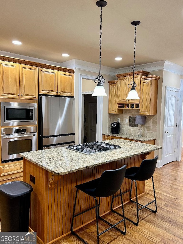 kitchen with light stone countertops, light hardwood / wood-style floors, decorative backsplash, a kitchen island, and appliances with stainless steel finishes