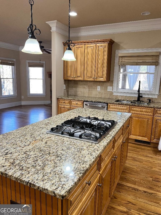 kitchen featuring decorative backsplash, appliances with stainless steel finishes, sink, pendant lighting, and a kitchen island