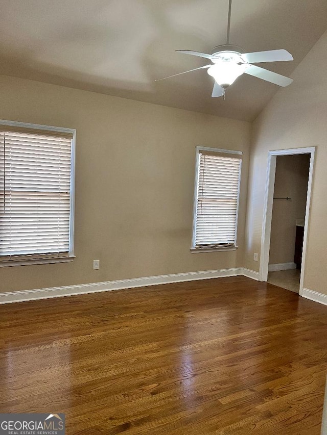 spare room featuring ceiling fan, a healthy amount of sunlight, dark hardwood / wood-style flooring, and lofted ceiling