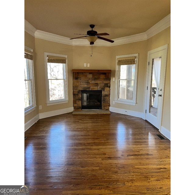 unfurnished living room with a fireplace, crown molding, ceiling fan, and dark wood-type flooring