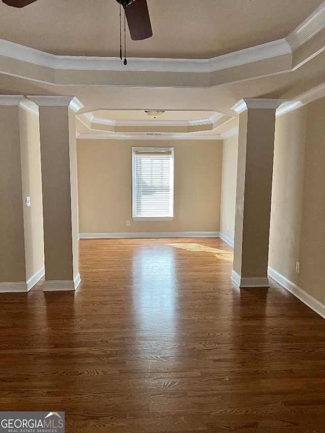 empty room featuring dark wood-type flooring, a raised ceiling, and ornamental molding