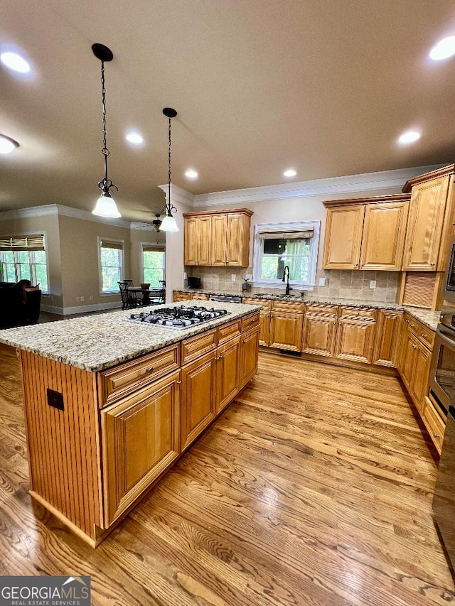 kitchen featuring stainless steel gas stovetop, a kitchen island, sink, and tasteful backsplash