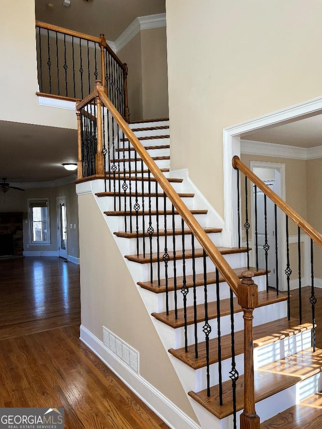 stairway featuring hardwood / wood-style floors, ceiling fan, and ornamental molding