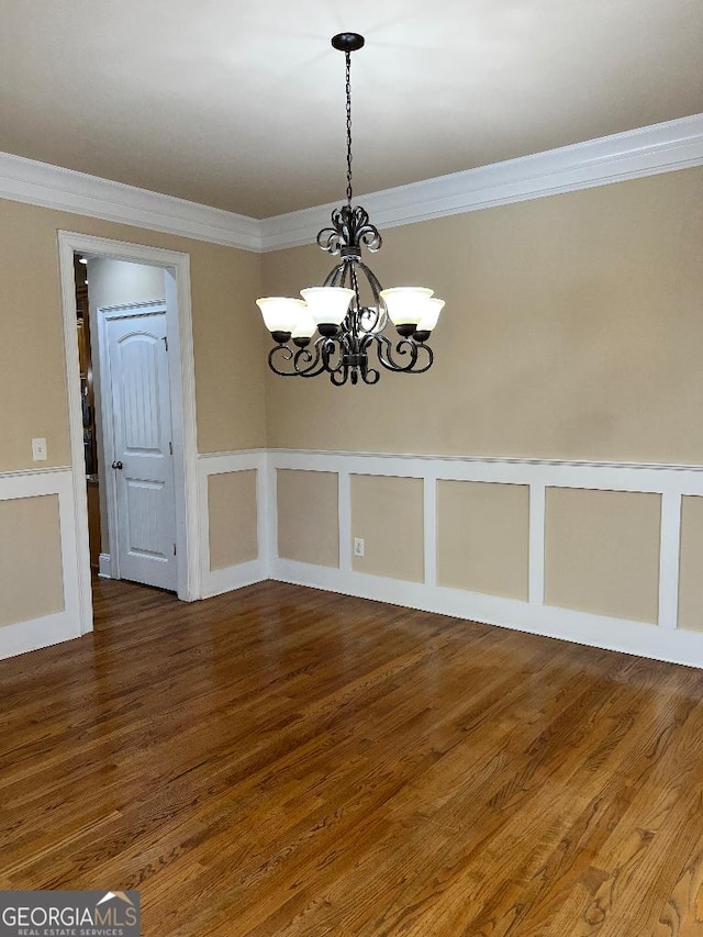 unfurnished dining area with wood-type flooring, ornamental molding, and a notable chandelier