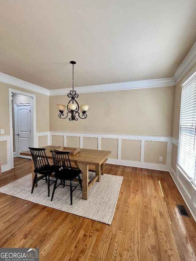 dining room with crown molding, light hardwood / wood-style flooring, and a notable chandelier