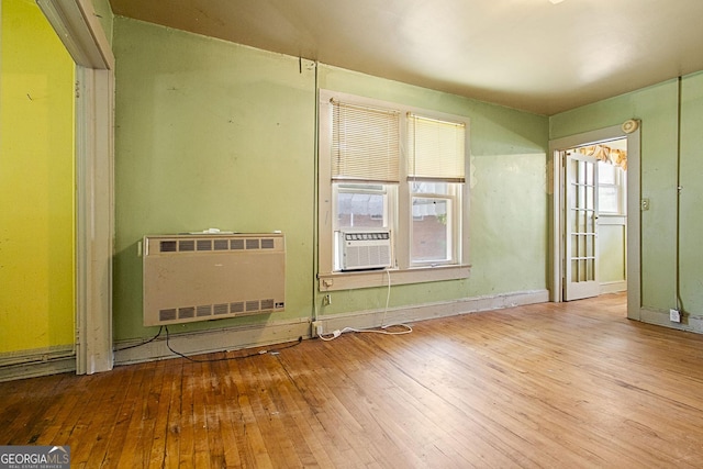 unfurnished room featuring hardwood / wood-style floors, plenty of natural light, cooling unit, and heating unit