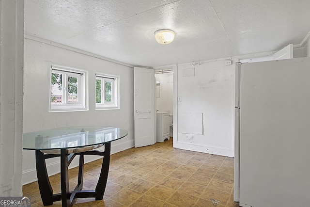 dining room featuring a textured ceiling, light floors, and baseboards