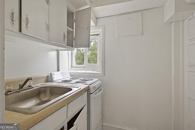 kitchen with light countertops, white cabinets, white electric range, and a sink