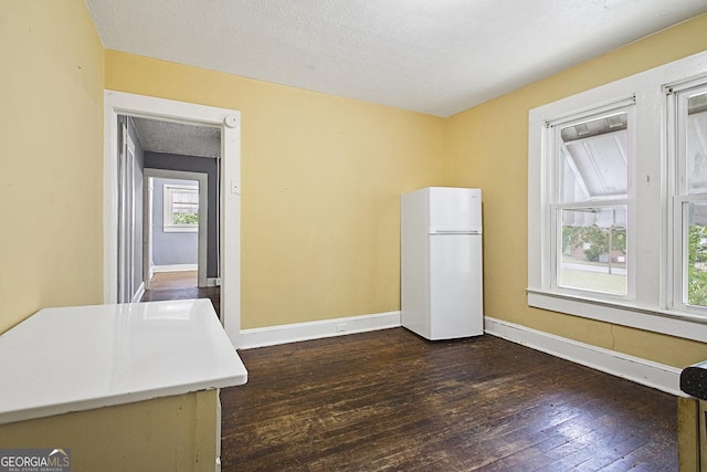 interior space featuring a textured ceiling, dark wood-style flooring, and baseboards