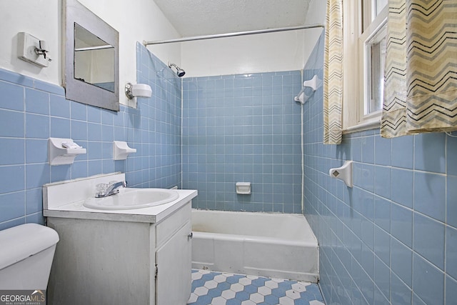 bathroom featuring shower / washtub combination, tile walls, toilet, vanity, and tile patterned floors