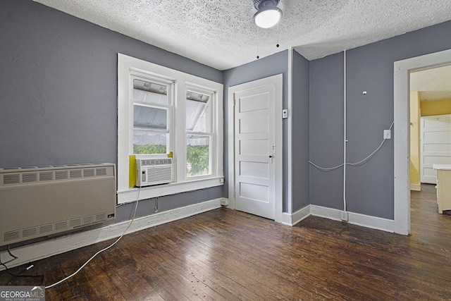 unfurnished bedroom featuring heating unit, hardwood / wood-style floors, a textured ceiling, cooling unit, and baseboards