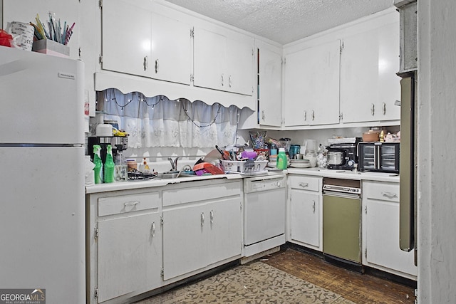 kitchen featuring a textured ceiling, light countertops, white appliances, and white cabinets