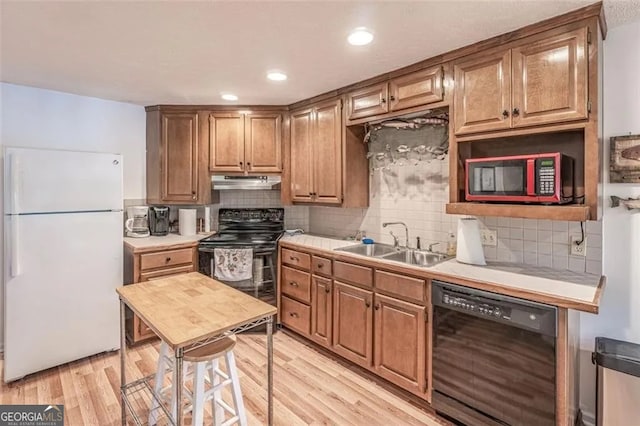 kitchen featuring black appliances, light hardwood / wood-style floors, sink, and tasteful backsplash