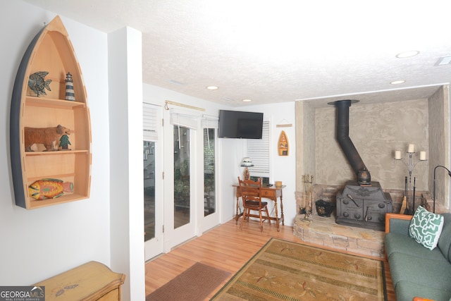 living room featuring a textured ceiling, hardwood / wood-style floors, and a wood stove