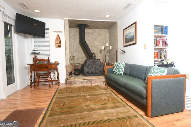 living room with a wood stove, a textured ceiling, and hardwood / wood-style floors