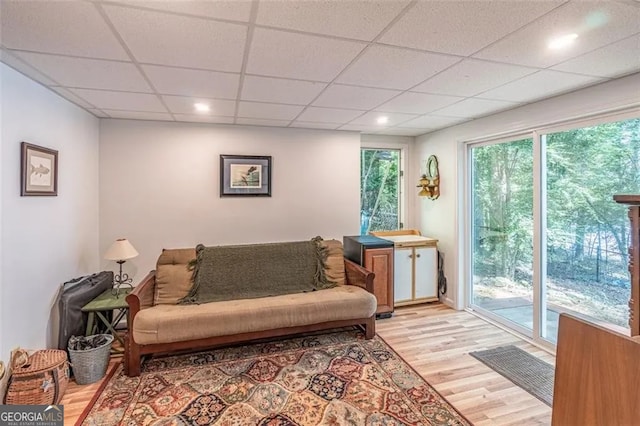 living room with a drop ceiling and light hardwood / wood-style floors