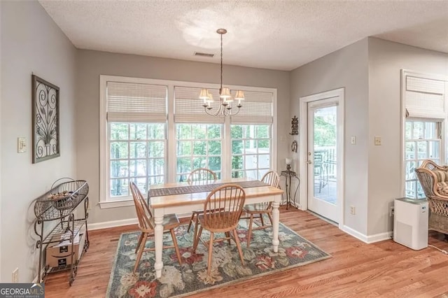 dining room featuring a healthy amount of sunlight, light hardwood / wood-style floors, and an inviting chandelier