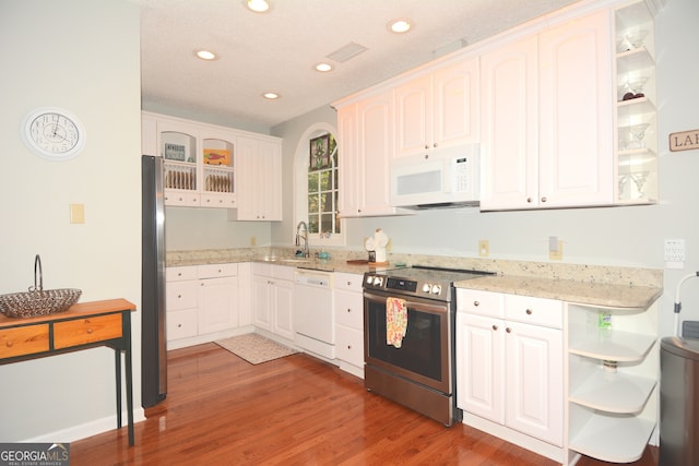 kitchen with light stone counters, sink, white cabinetry, stainless steel appliances, and hardwood / wood-style floors